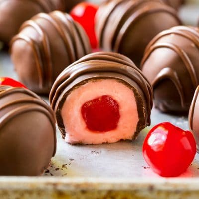 Chocolate covered cherries dipped in dark chocolate with a decorative drizzle.