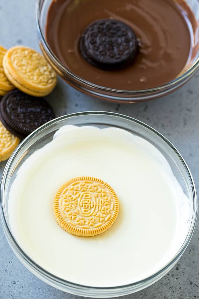 Oreos being dipped into dark and white chocolate.
