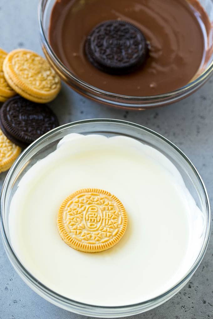 Cookies being dipped into dark and white chocolate.