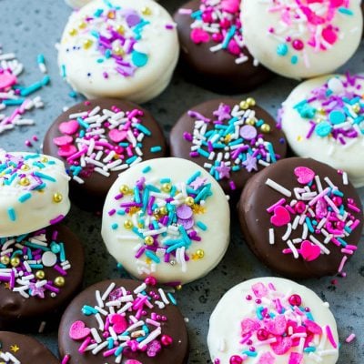 Chocolate covered Oreos decorated with pink and purple sprinkles.