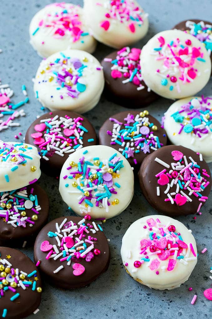 Chocolate covered Oreos decorated with pink and purple sprinkles.