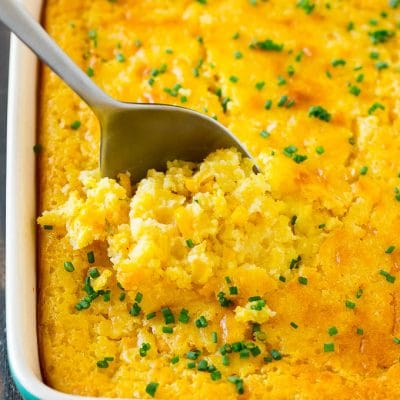 A pan of corn pudding with a serving spoon in it.