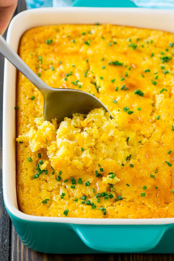 A pan of corn pudding with a serving spoon in it.