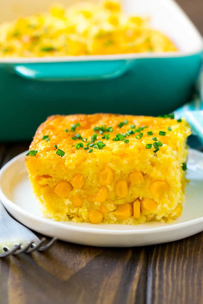 A serving of corn pudding on a plate, garnished with chives.