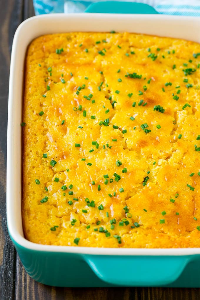 A casserole dish of corn pudding topped with chives.