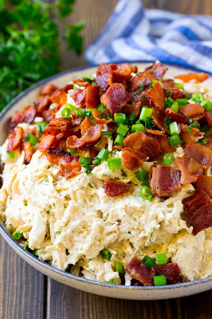 A bowl of crack chicken topped with bacon and green onions.