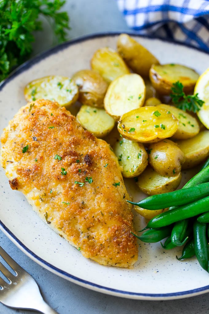 A plate of Italian chicken, roasted potatoes and green beans.