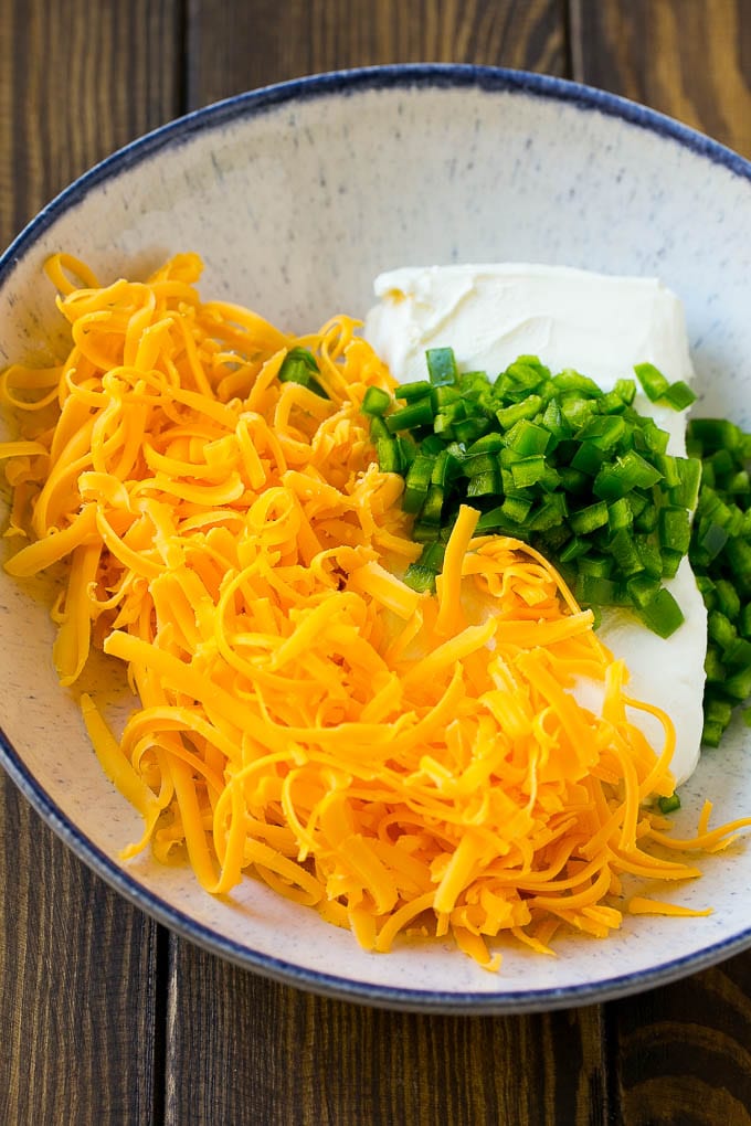 Cheddar cheese, cream cheese and diced jalapenos in a bowl.