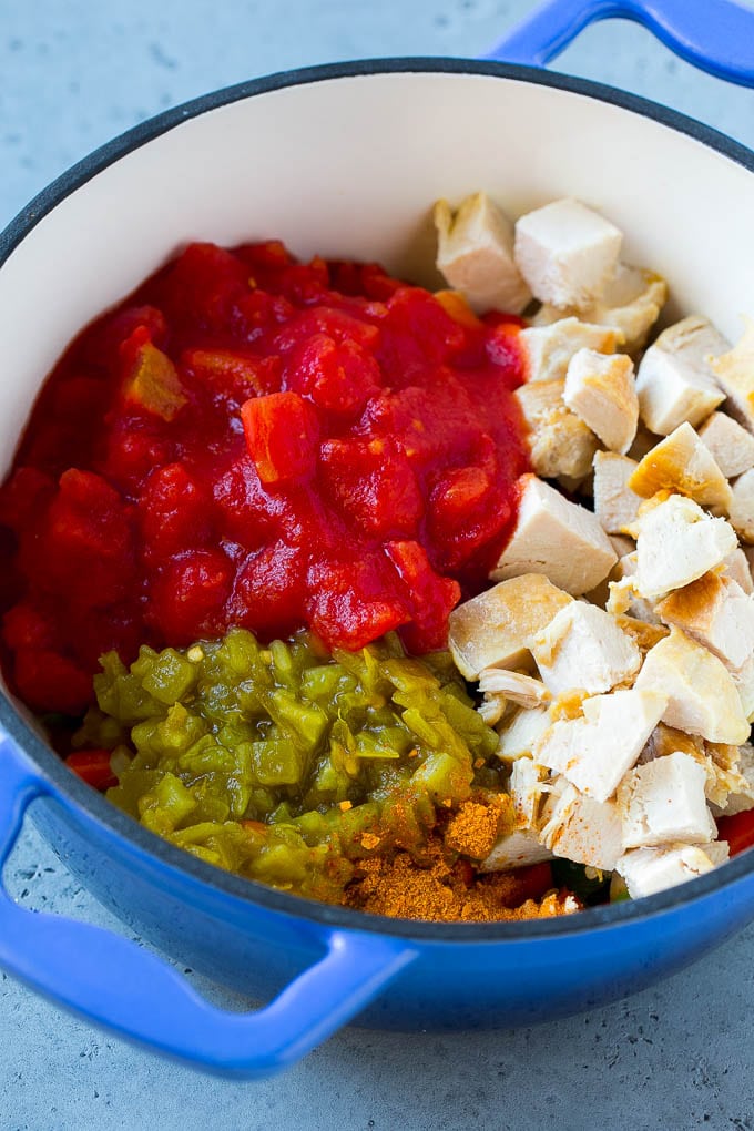 Vegetables, chicken, chiles and tomatoes in a pot.