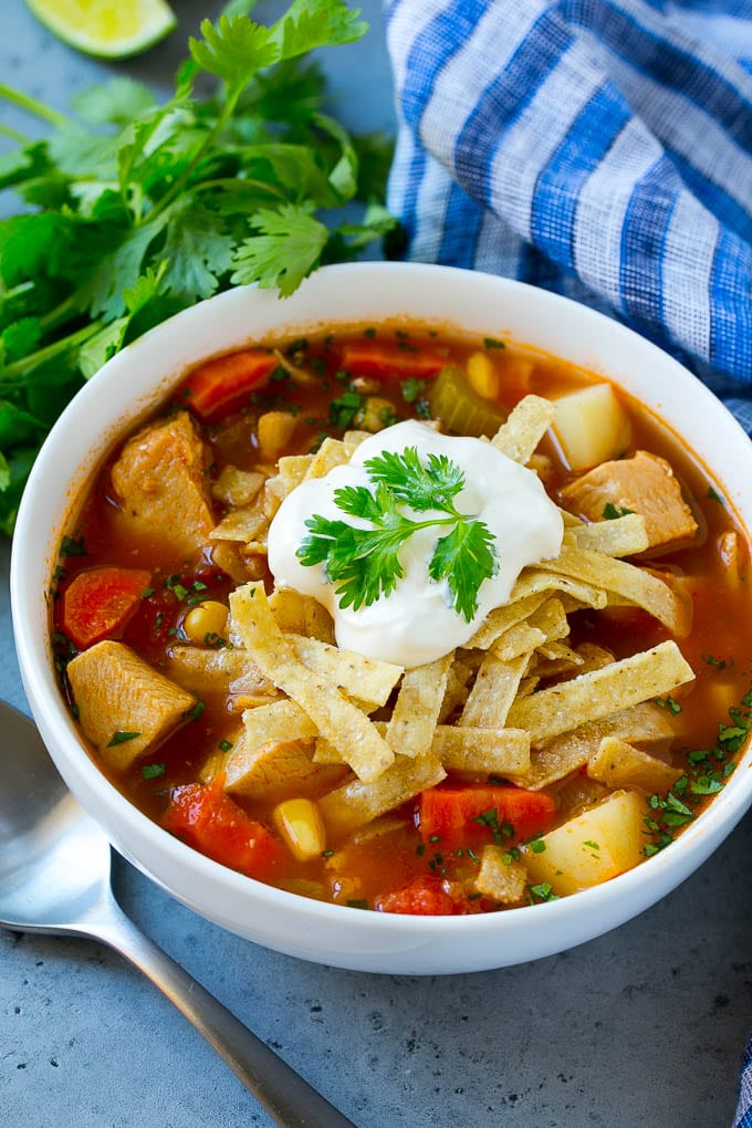 A bowl of Mexican chicken soup topped with tortilla strips and sour cream.