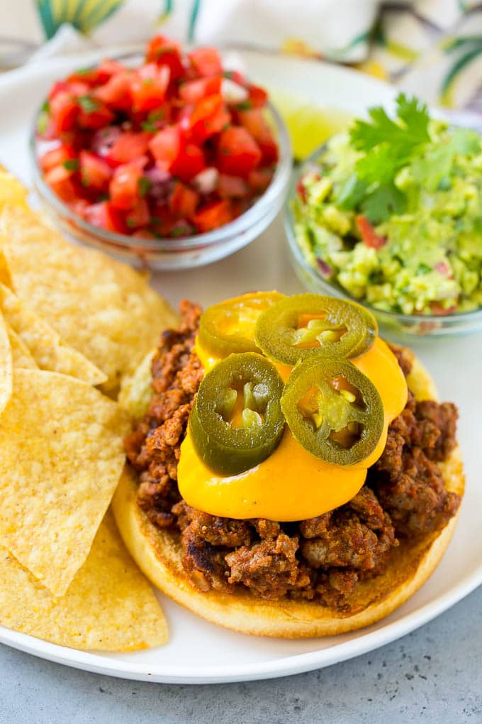 A hamburger bun with sloppy joe meat, nacho cheese sauce and jalapenos.