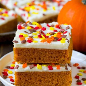 A stack of pumpkin bars topped with frosting and sprinkles.
