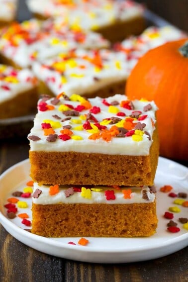 A stack of pumpkin bars topped with frosting and sprinkles.