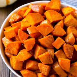 A bowl of maple roasted sweet potatoes with cinnamon and butter.
