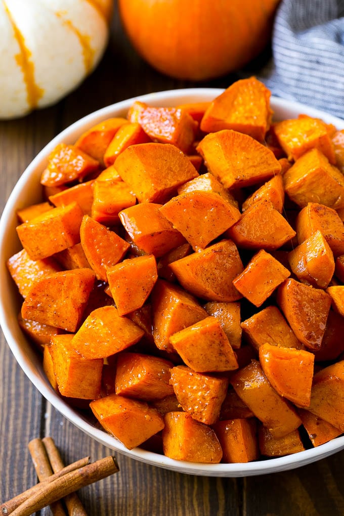 A bowl of maple roasted sweet potatoes with cinnamon and butter on top.