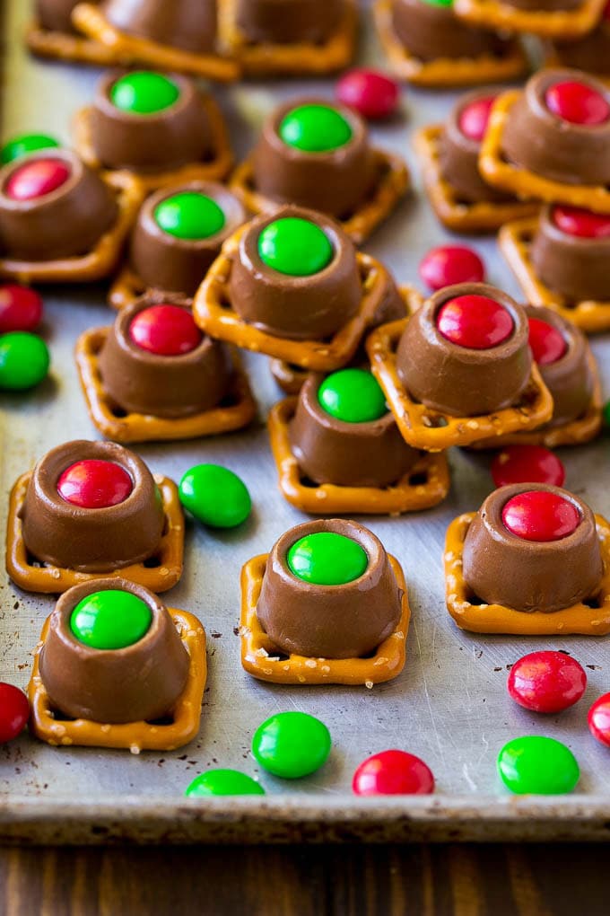 Rolo pretzels on a baking sheet topped with red and green M&M's.