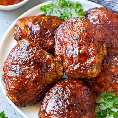 A plate of smoked chicken thighs coated in spice rub and barbecue sauce.