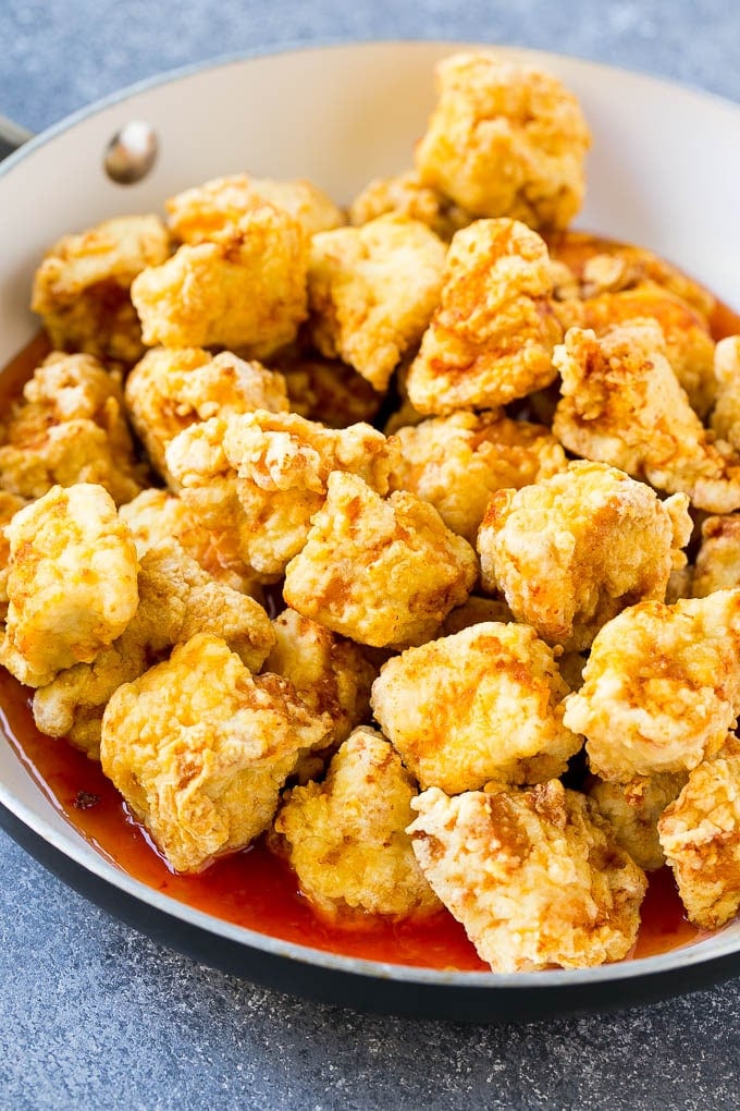 Crispy chicken breast pieces with sweet chili sauce in a pan.