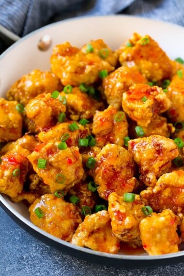 Sweet chili chicken in a skillet, topped with sliced green onions.