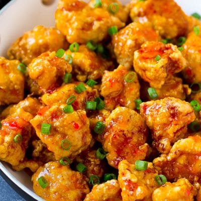 Sweet chili chicken in a skillet, topped with sliced green onions.