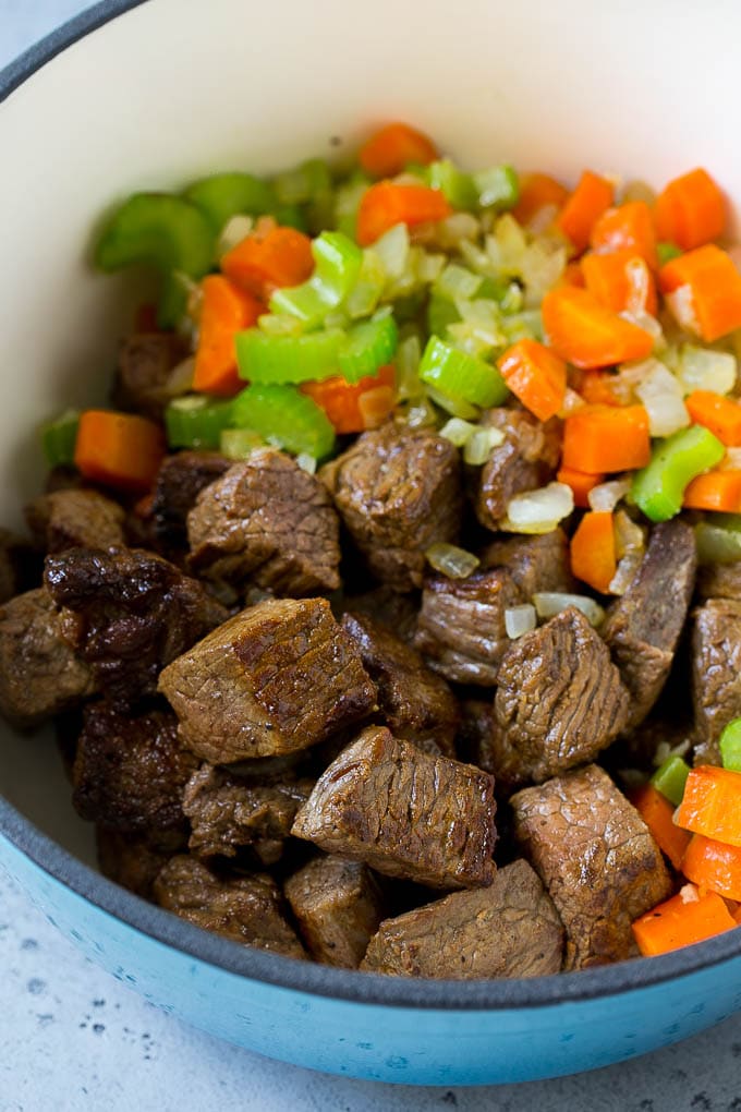 Beef stew meat, carrots, onions and celery in a soup pot.