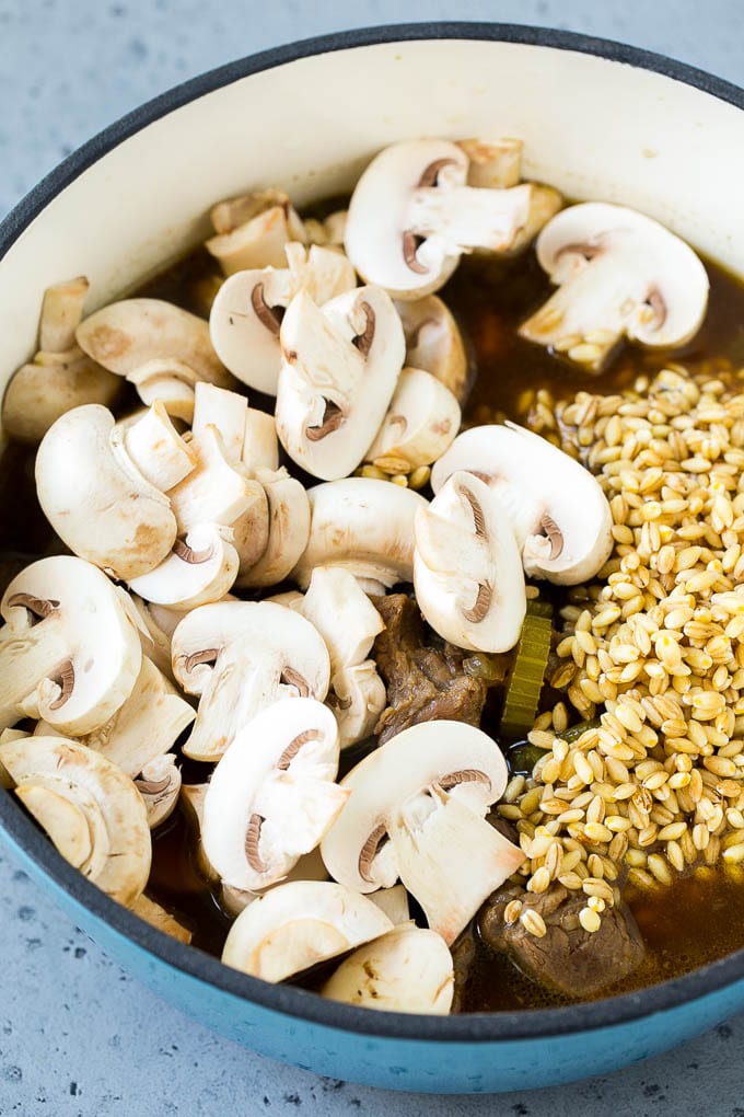 Beef barley soup with sliced mushrooms and barley stirred in.