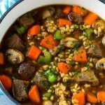 A pot full of beef barley soup made with beef stew meat, barley and vegetables all simmered together.