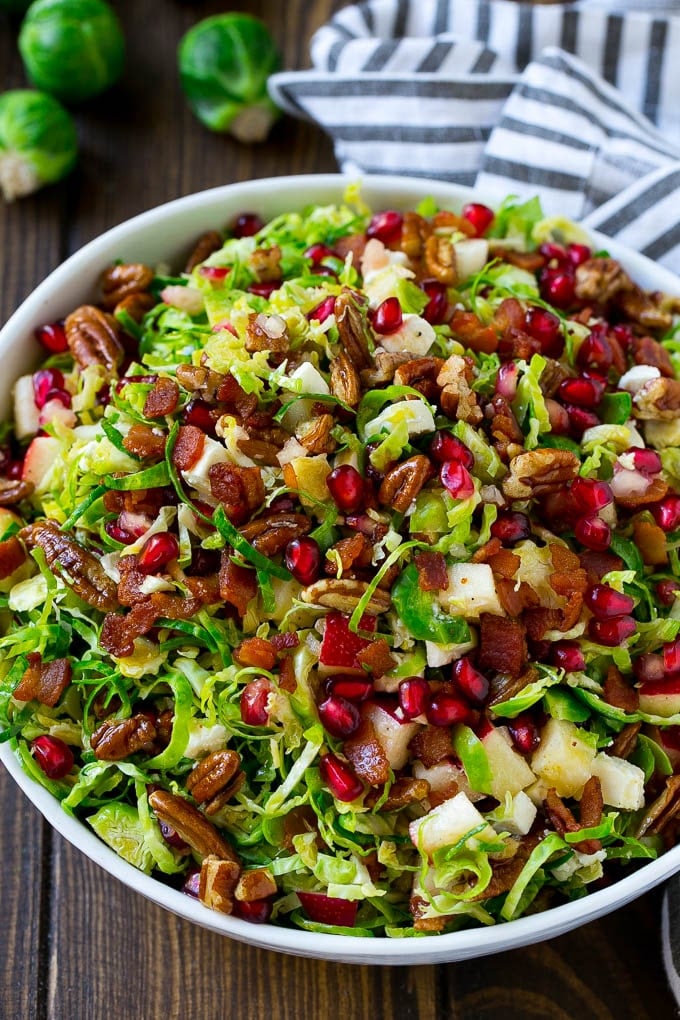 A bowl of salad made with pomegranate, bacon and apples.