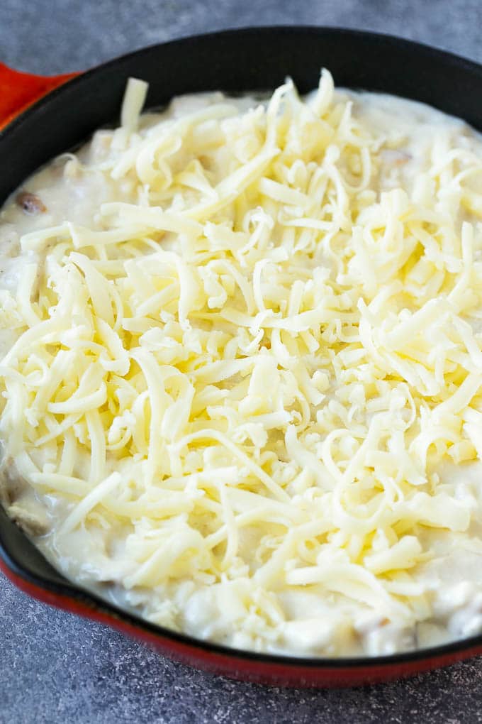 A skillet of chicken Alfredo dip topped with shredded mozzarella cheese.