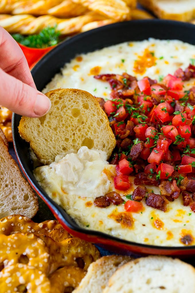 A crostini scooping out a serving of chicken Alfredo dip.