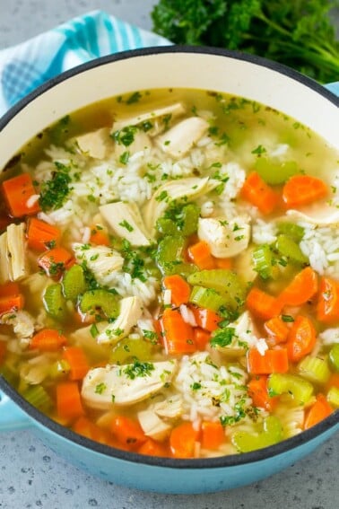 A pot of chicken and rice soup with carrots, celery, chicken breast and white rice.