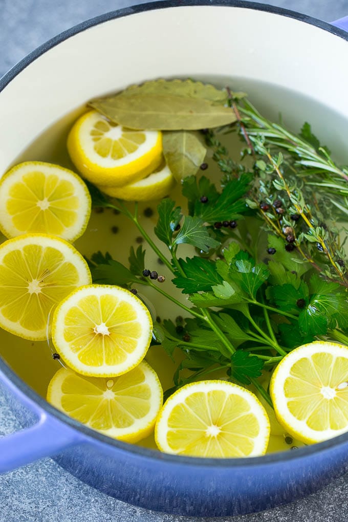 Salt, water, lemons, herbs and peppercorns in a pot.