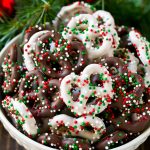 Chocolate covered pretzels in a bowl with Christmas sprinkles.