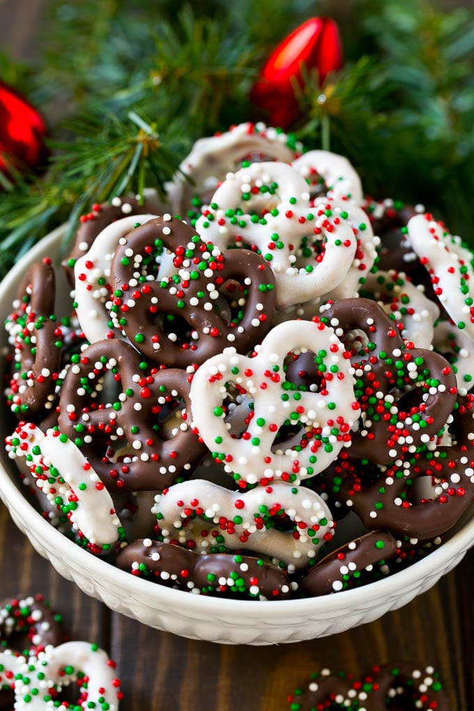 Chocolate covered pretzels in a bowl with Christmas sprinkles.