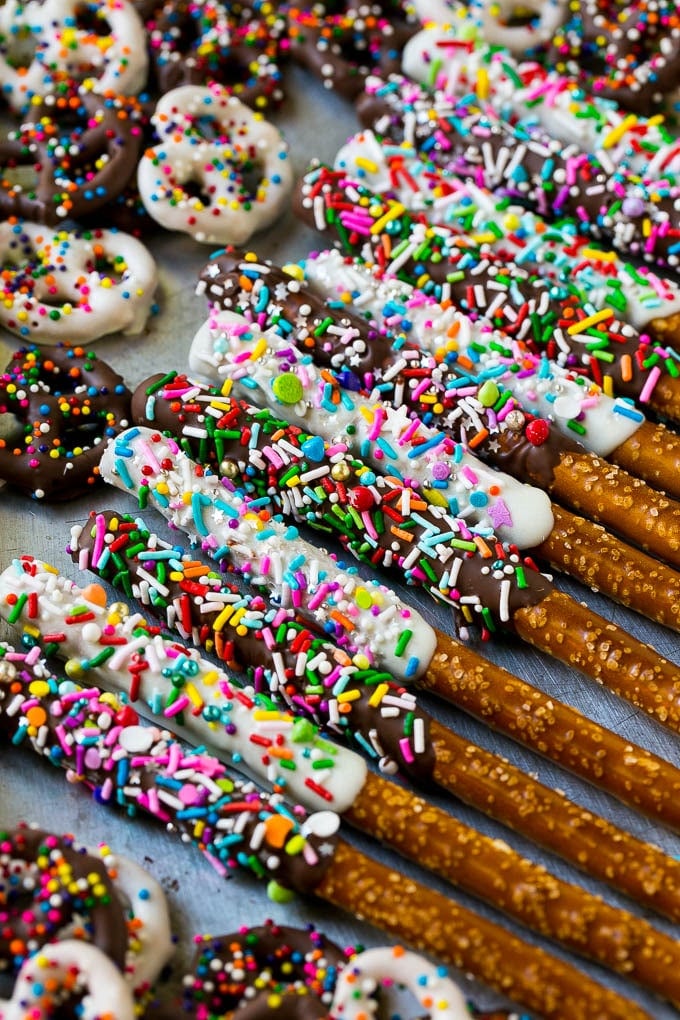 A sheet pan with coated twists and rods decorated with rainbow sprinkles.