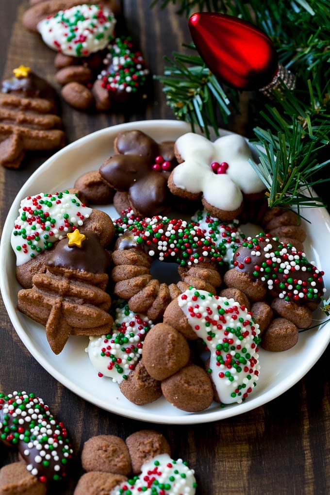 Chocolate spritz cookies coated in sprinkles on a serving plate.