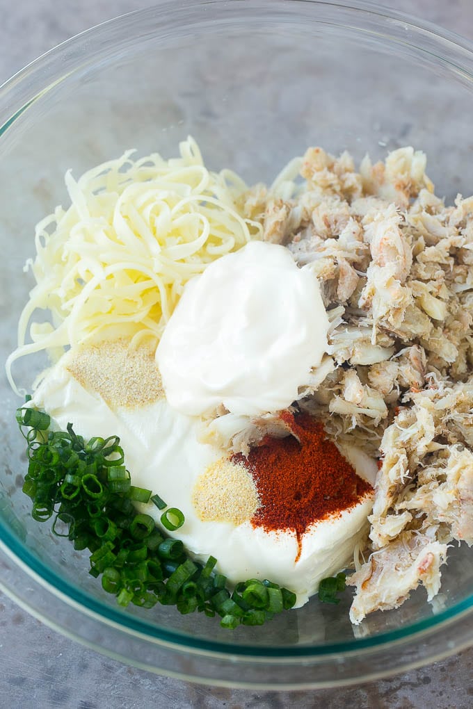 Crab, cream cheese, mayonnaise, green onions and spices in a mixing bowl.