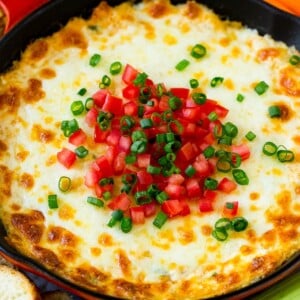 Hot crab dip in a skillet topped with tomatoes and green onions.