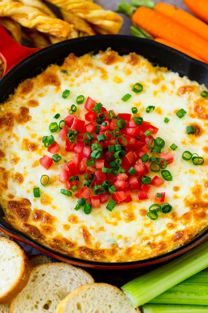 Hot crab dip in a skillet topped with tomatoes and green onions.