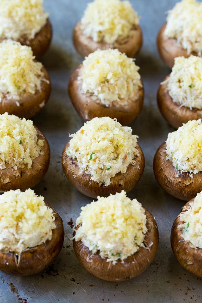 Uncooked crab stuffed mushrooms on a sheet pan.