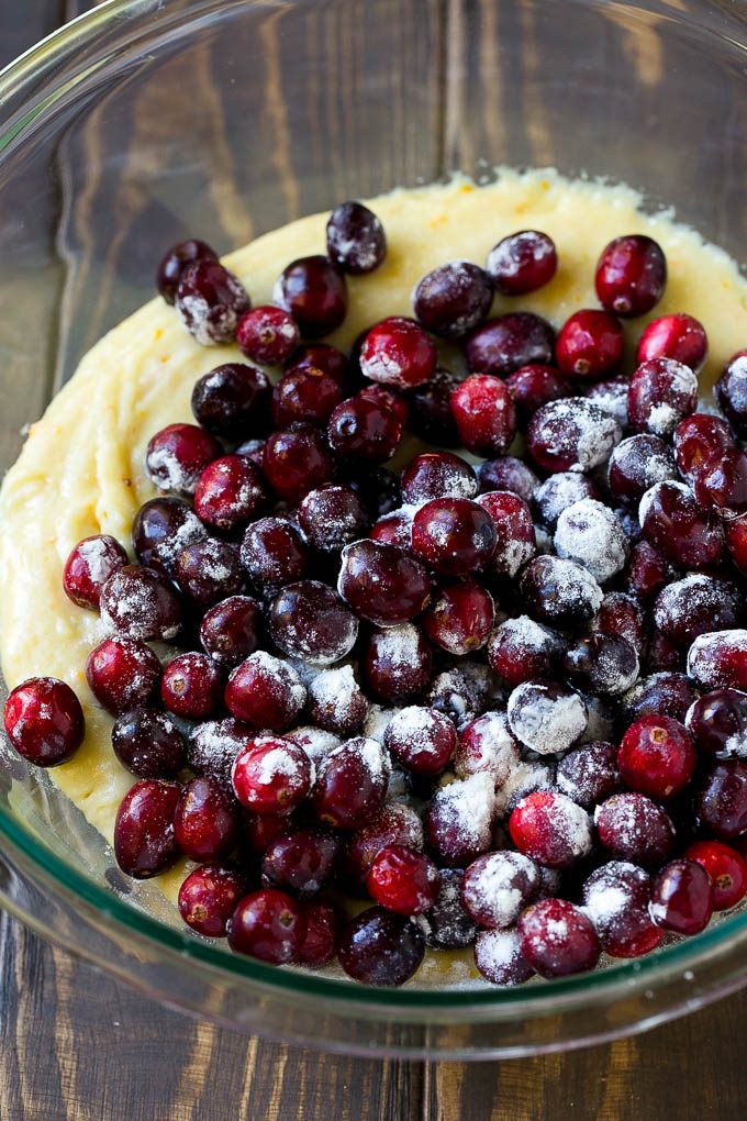 Orange batter topped with a pile of fresh cranberries in a mixing bowl.