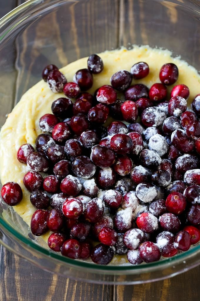 Cranberry Bread Recipe | Cranberry Loaf | Cranberry Orange Bread #cranberry #bread #baking #dessert #fall #dinneratthezoo Orange batter topped with a pile of fresh cranberries in a mixing bowl.