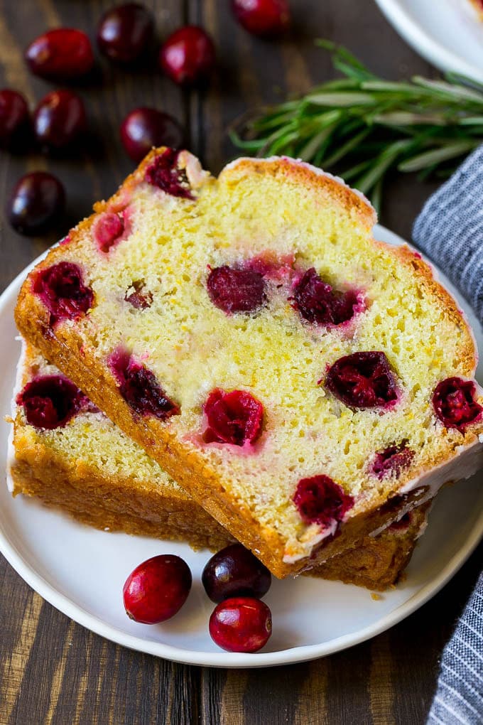 A plate with two slices of cranberry bread and fresh cranberries for garnish.