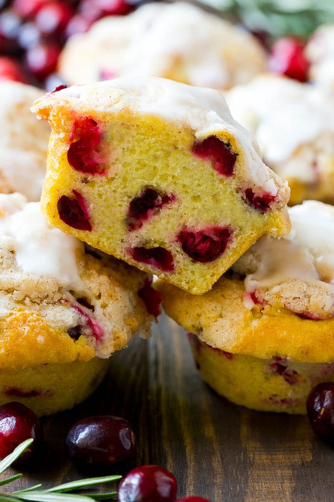 A stack of cranberry muffins with one muffin cut in half.