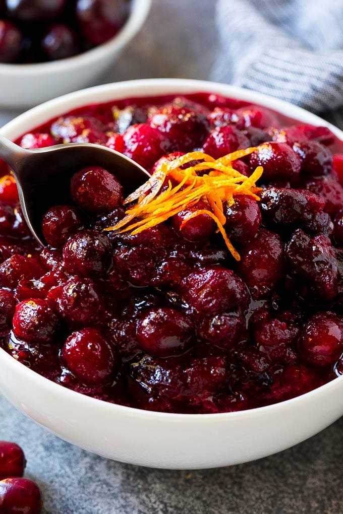 A serving spoon in a bowl of cranberry orange sauce.