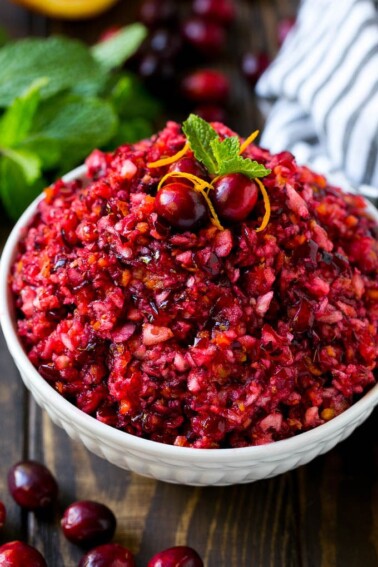A bowl of cranberry relish topped with whole cranberries, orange zest and mint.