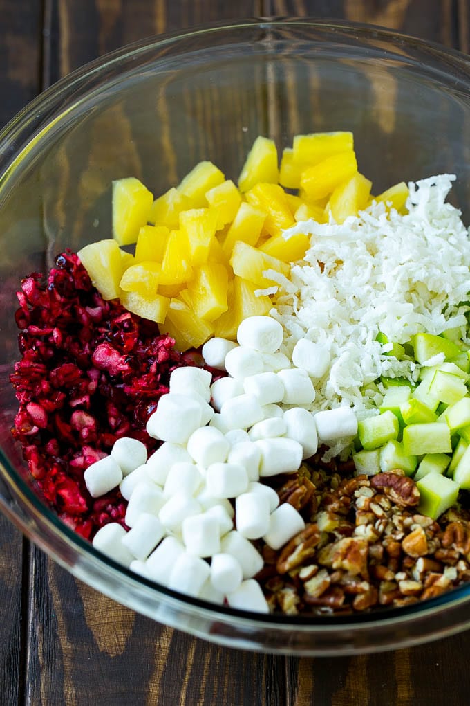 Chopped cranberries, apples, pineapple, marshmallows, pecans and coconut in a mixing bowl.