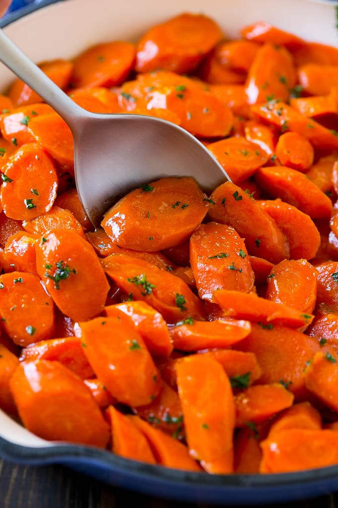 Glazed carrots in a skillet with a serving spoon.