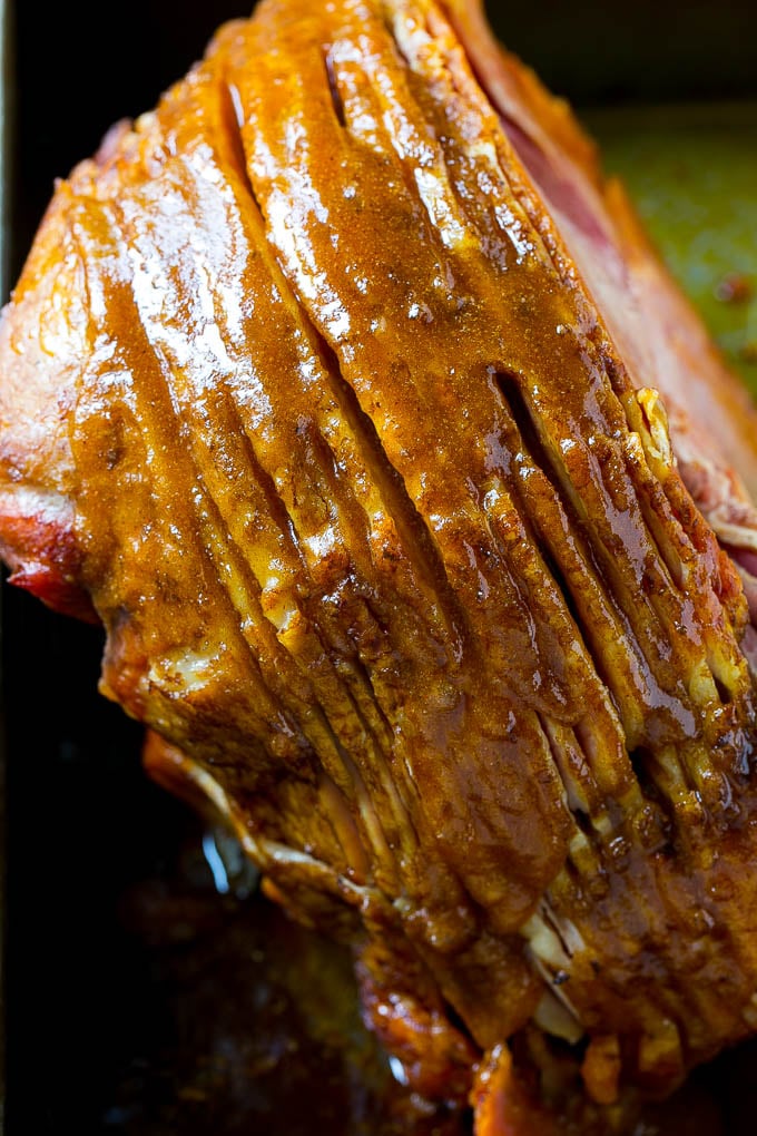 A ham coated in sugar glaze in a baking pan.
