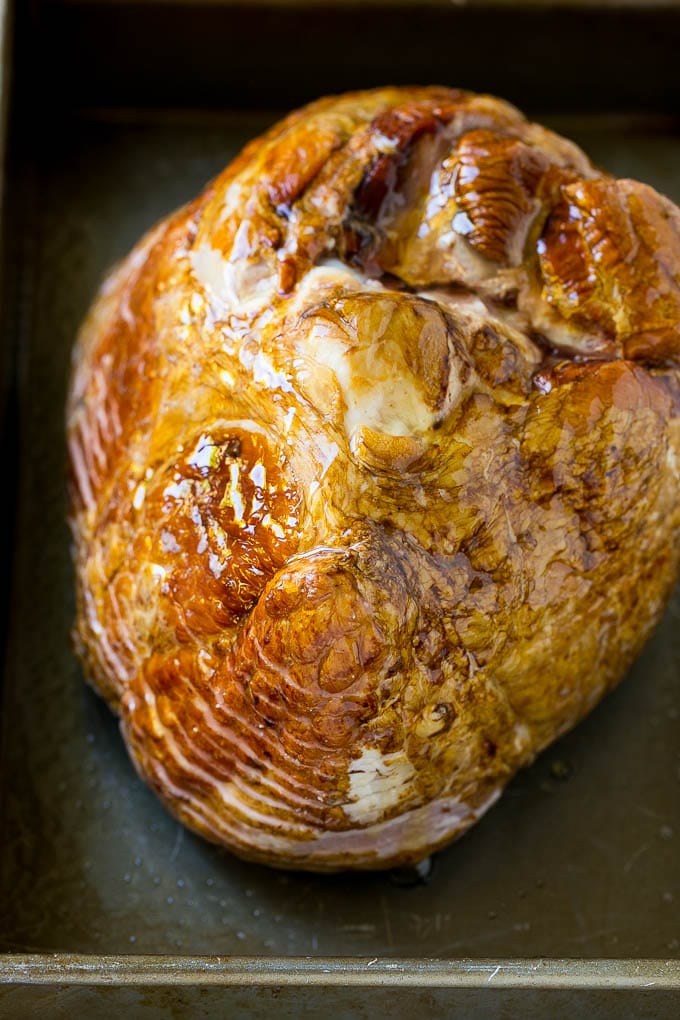 A honey coated ham, face down, in a baking dish.